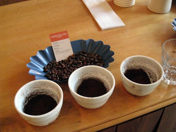 multiple cups filled with ground coffee beans